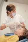 Жінка в масці і лікар рівномірний рішень сканування зубів маленького хлопчика при роботі в стоматологічному клініці — стокове фото