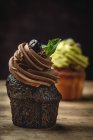 Delicioso chocolate caseiro e cupcakes de hortelã em fundo rústico desfocado — Fotografia de Stock