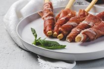 Gressinis con jamón serrano típico español en bandeja blanca - foto de stock