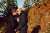 Glückliches homosexuelles Paar umarmt sich an sonnigem Tag auf Waldweg — Stockfoto