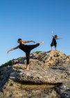 Молоді таємничі балерини в чорному одязі танцюють на каменях у сонячний день — стокове фото