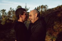 Felice coppia omosessuale abbraccio sul sentiero nella foresta nella giornata di sole — Foto stock