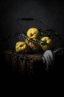 Manzanas-membrillos amarillos maduros colocados en cesta sobre fondo de madera oscura - foto de stock
