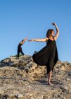 Молоді таємничі балерини в чорному одязі танцюють на скелях у сонячний день. — стокове фото