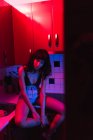 Sensual young brunette woman in lingerie looking at camera and sitting in kitchen between redness — Stock Photo