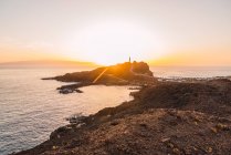 Скелястий берег з дорогою і маяка біля моря ввечері на Тенеріфе, Канарські острови, Іспанія — стокове фото