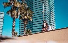 Adolescente regardant la rue tout en écoutant de la musique avec ses casques et son smartphone — Photo de stock