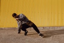 Хлопець танцює біля стіни сучасної будівлі на міській вулиці — стокове фото