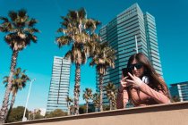 Teenie-Mädchen schaut an einem sonnigen Tag auf der Straße auf ihr Smartphone — Stockfoto