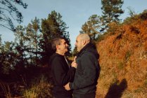 Happy homosexual couple hugging on path in forest in sunny day — Stock Photo