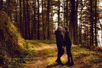 Гомосексуальная пара обнимается и целуется по дороге в лес в солнечный день — стоковое фото