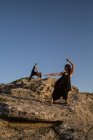 Молоді таємничі балерини в чорному одязі танцюють на каменях у сонячний день — стокове фото