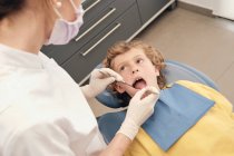 Mani del medico fare la scansione dei denti del bambino mentre si lavora in clinica dentista — Foto stock