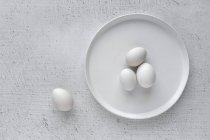 Ovos brancos na placa na mesa de madeira — Fotografia de Stock