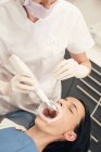 Zahnarzthände in Handschuhen mit modernen Geräten für die Zähne von Patientinnen in Zahnarztpraxen — Stockfoto