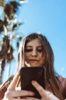 Menina adolescente olhando para seu smartphone na rua em um dia ensolarado — Fotografia de Stock