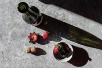 Morangos frescos na tigela e na superfície cinzenta com garrafa de vinho — Fotografia de Stock