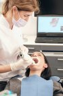 Mulher em luvas e máscara usando equipamentos modernos para varredura de dentes de paciente do sexo feminino em consultório odontológico — Fotografia de Stock