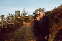 Glückliches homosexuelles Paar umarmt und küsst sich an sonnigem Tag auf Waldweg — Stockfoto
