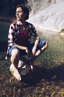 Щаслива доросла жінка сидить на скелі в спокійній прозорій воді озера насолоджується природою і посміхається — стокове фото