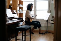 Чёрная женщина играет на гитаре во время репетиции в студии звукозаписи — стоковое фото