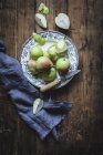 Juicy fresh pears on plate on wooden table with knife and napkin — Stock Photo