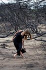 Jeune ballerine en tenue noire posant entre des bois secs — Photo de stock