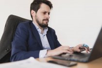 Jóvenes concentrados navegando en el ordenador portátil en la mesa en la oficina - foto de stock