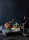 Sandwich di patè di pomodori secchi, insalata fresca e cavolo su vassoio vicino a coltello su asse di legno su sfondo nero — Foto stock
