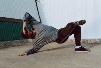 Ragazzo elegante che esegue stand e ballando vicino al muro di edificio moderno sulla strada della città — Foto stock