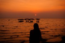 Frau bei Sonnenuntergang in der Nähe von Wäscherei im Meer — Stockfoto
