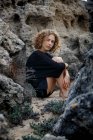 Молода вдумлива жінка сидить у скелях і обіймає коліна — стокове фото