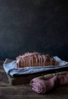 Frischer leckerer Orangenkuchen mit Mohn und Belag auf Bastelpapier auf schwarzem Hintergrund — Stockfoto