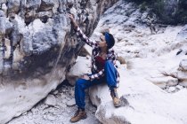Зверху приваблива усміхнена жінка відпочиває на скелі на горі — стокове фото