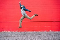 Schöner bärtiger Mann in lässigem Outfit, der wegschaut, während er in der Nähe der roten Backsteinmauer auf der Stadtstraße aufspringt — Stockfoto