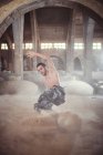 Male dancing in sand cloud old building — Stock Photo