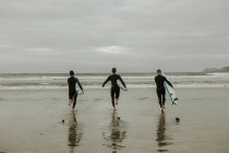 Persone con tavola da surf a piedi vicino al mare — Foto stock