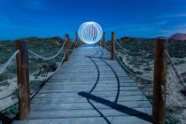 Белый абстрактный шар, левитирующий над пешеходным мостом между землями и голубым небом вечером — стоковое фото