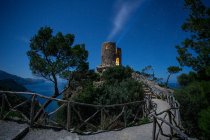 Luces desde la torre en la cima de la colina alta cerca del mar y el cielo maravilloso en la noche - foto de stock
