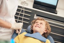 Female doctor in uniform speaking to little patient in dentist office — Stock Photo
