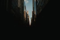 Perspektivischer dunkler Straßenblick zwischen glänzenden GlasWolkenkratzern im Sonnenlicht, New York — Stockfoto