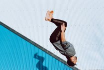 Homme pieds nus en tenue élégante effectuant flip près du mur du bâtiment moderne — Photo de stock
