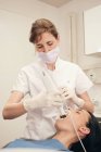 Femme dans les gants et le masque en utilisant un équipement moderne pour le balayage des dents de la patiente dans le cabinet de dentiste — Photo de stock