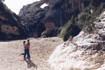 Junges Paar umarmt sich im Canyon zwischen Felsenbergen bei sonnigem Tag — Stockfoto