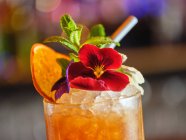 Cocktail decorato con frutta e fiori su sfondo sfocato — Foto stock