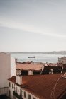 Изумительный вид беспилотника на голубое небо над черепичными крышами старых домов и спокойное море в Лиссабоне, Португалия — стоковое фото