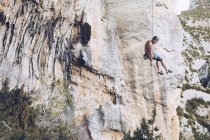 Dal basso di arrampicatore appeso su corda su ruvida scogliera contro cielo blu — Foto stock