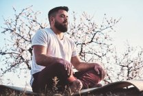 Бородатый мужчина медитирует в весеннем саду — стоковое фото