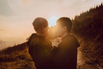 Романтична гомосексуальна пара обіймає шлях у горах у яскравому сонячному світлі на заході сонця — стокове фото