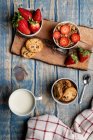 Glass and bottle of milk and pile of fresh cookies on wooden board near napkin — Stock Photo